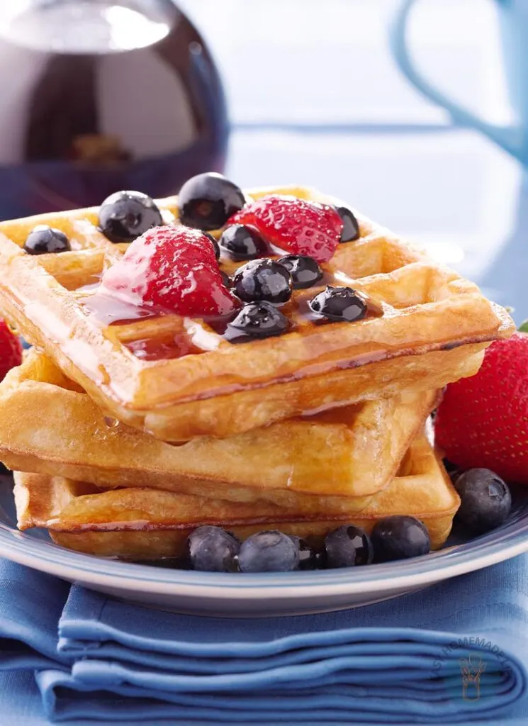 Waffles in a stack garnished with berries.