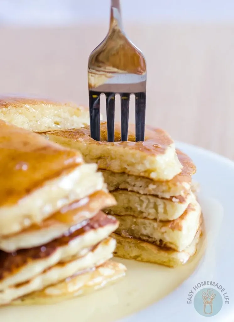 A stack of copycat McDonald's pancakes on a white plate with one side cut into a triangle portion on a fork.