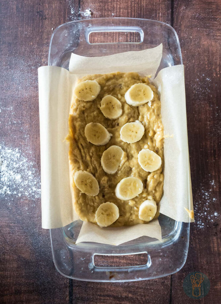 Banana bread mixture with sliced banana toppings in a baking dish.