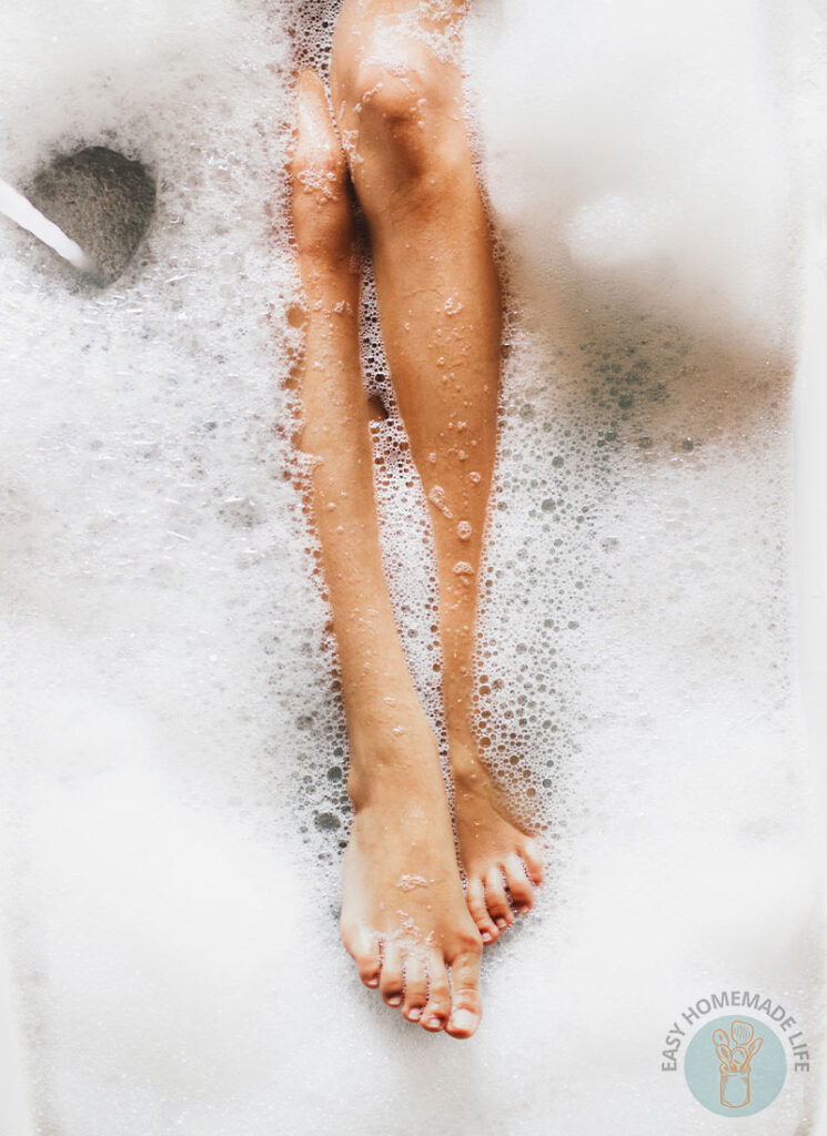 Two legs of a person in a bubble bath.