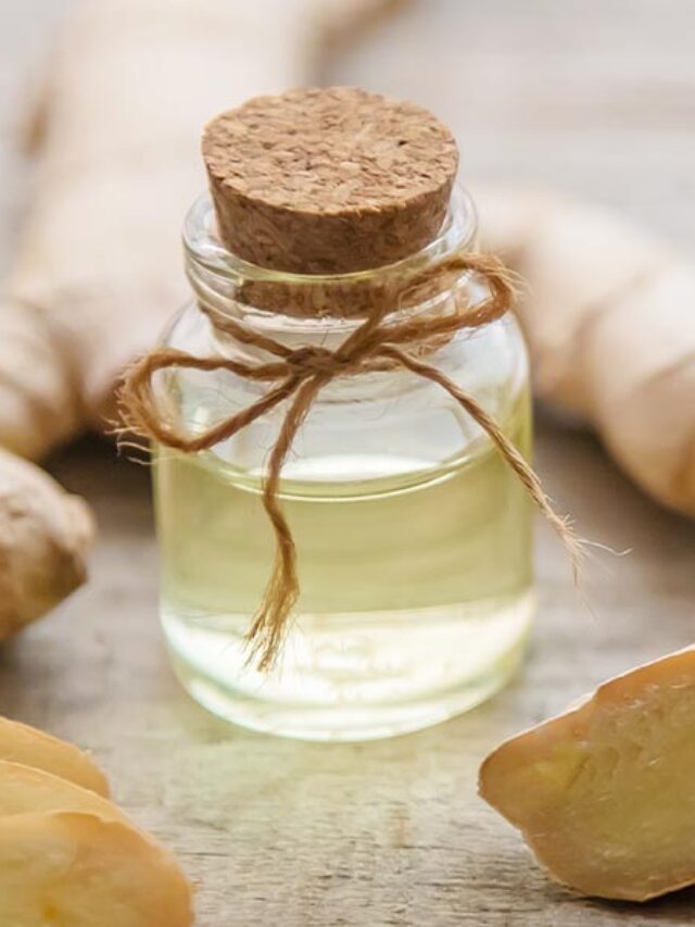 A bottle of ginger oil next to some ginger.