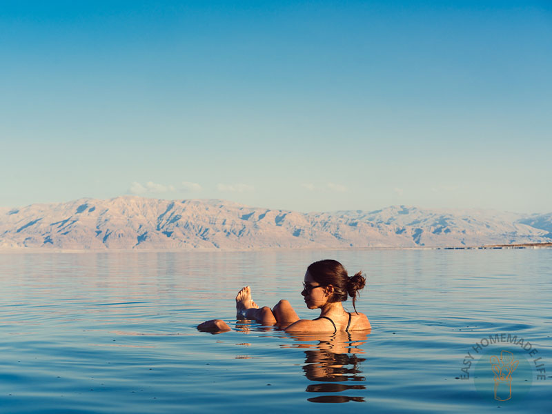 A woman in a lake with the view of the mountains in the background.