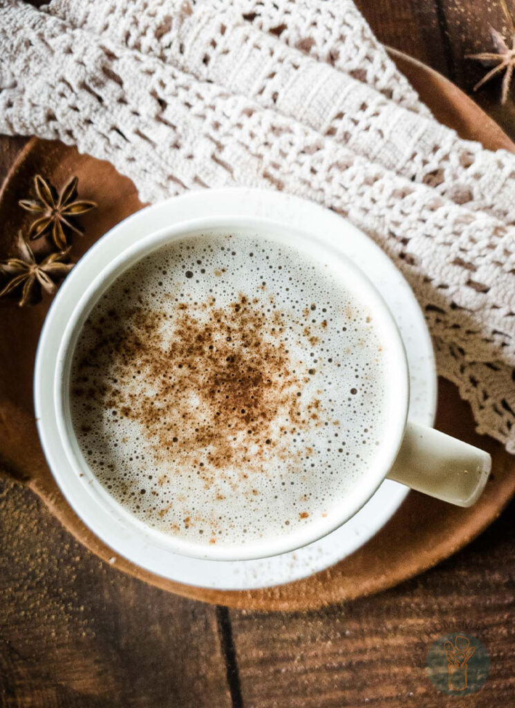 Chocolate chai tea in white teacup on clay dish garnished with cinnamon.