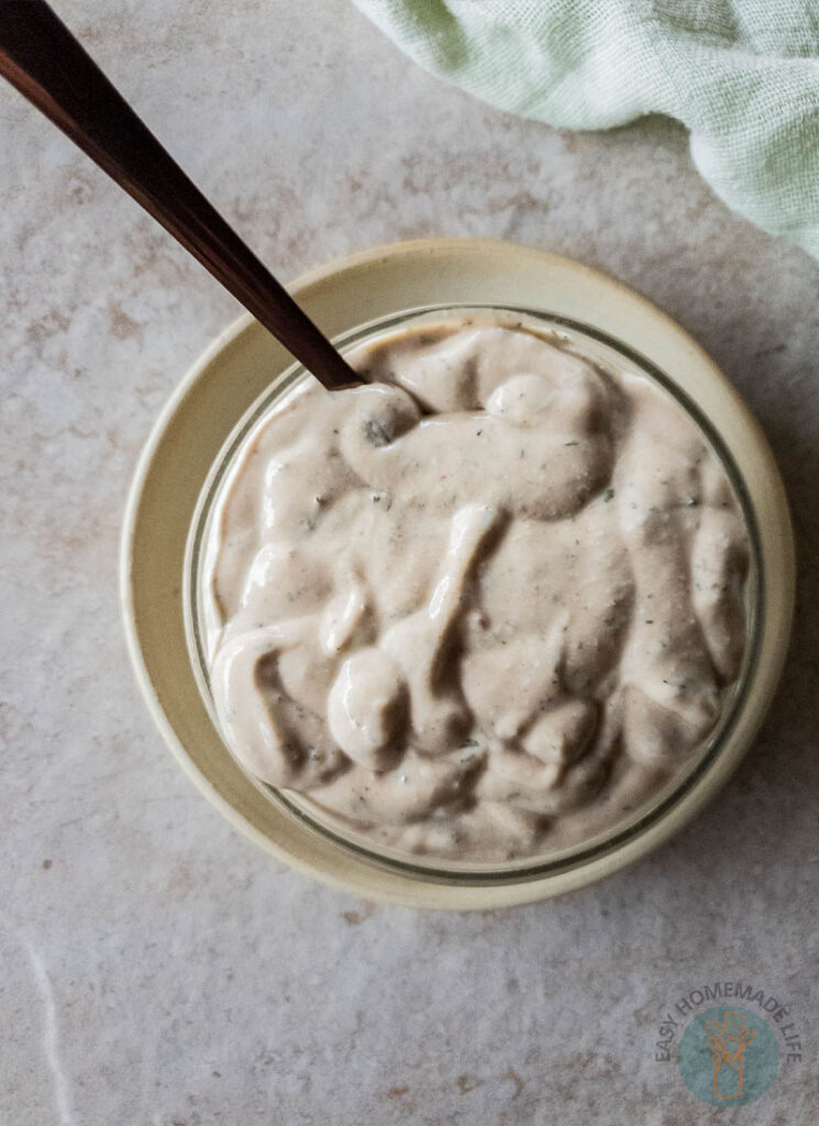 White sauce in a bowl next to a green napkin.