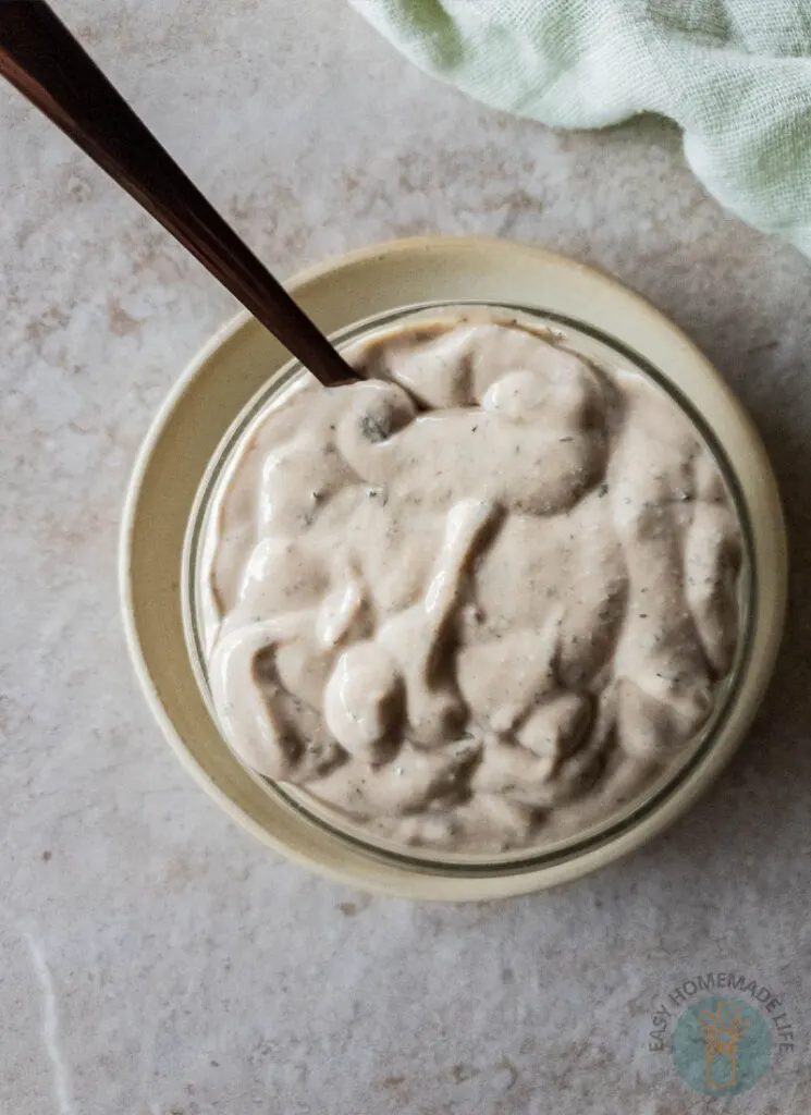 White sauce in a bowl next to a green napkin.