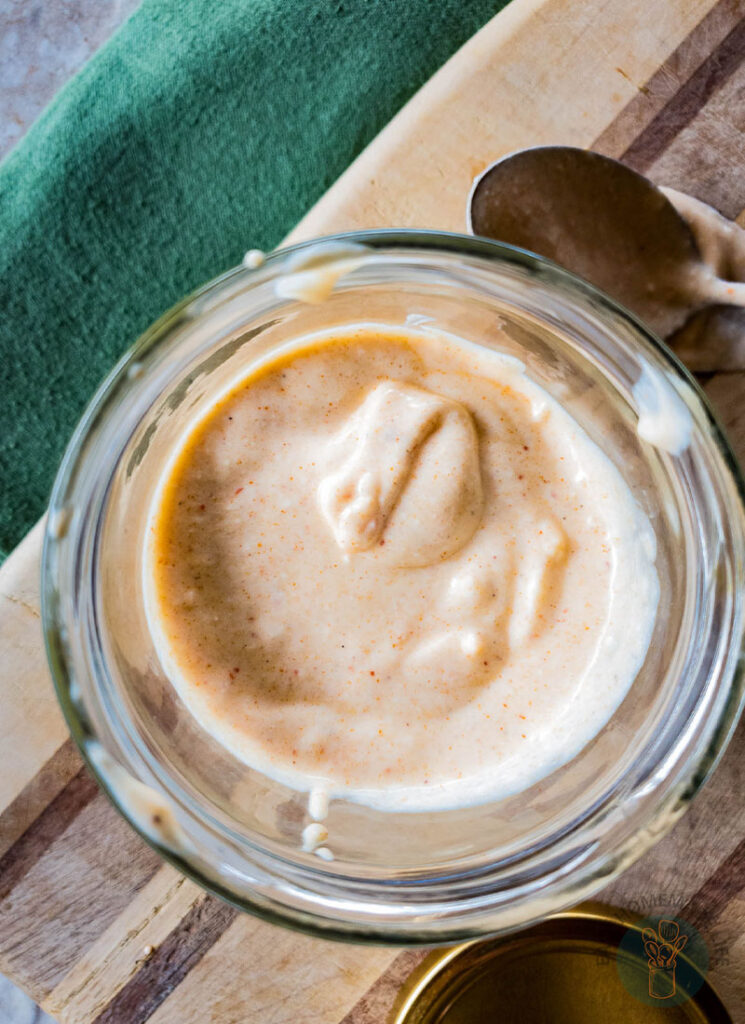 A jar of tiger sauce next to a spoon.