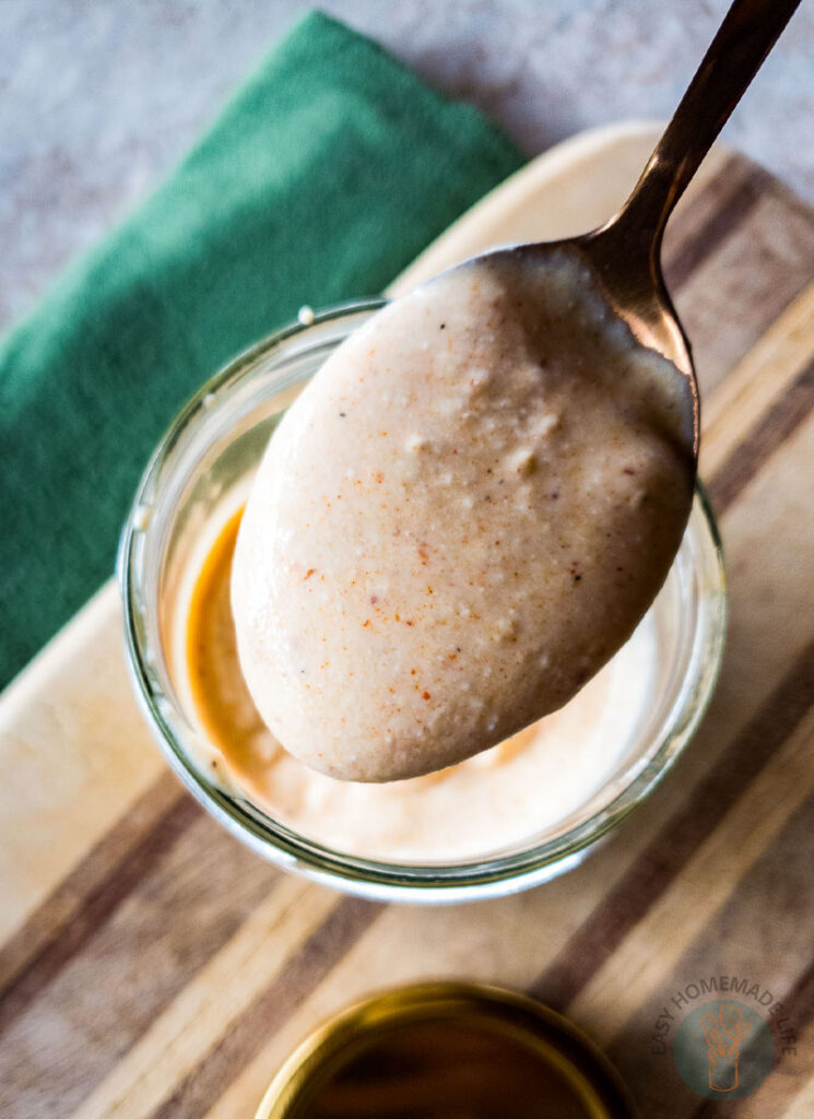 A spoonful of tiger sauce above the jar of the same sauce.