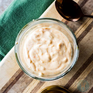 A jar of tiger sauce next to a spoon ready to be served.