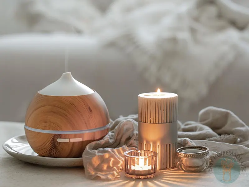 Essential oil diffuser next to a tall lit candle, a small lit candle and an unlit candle.