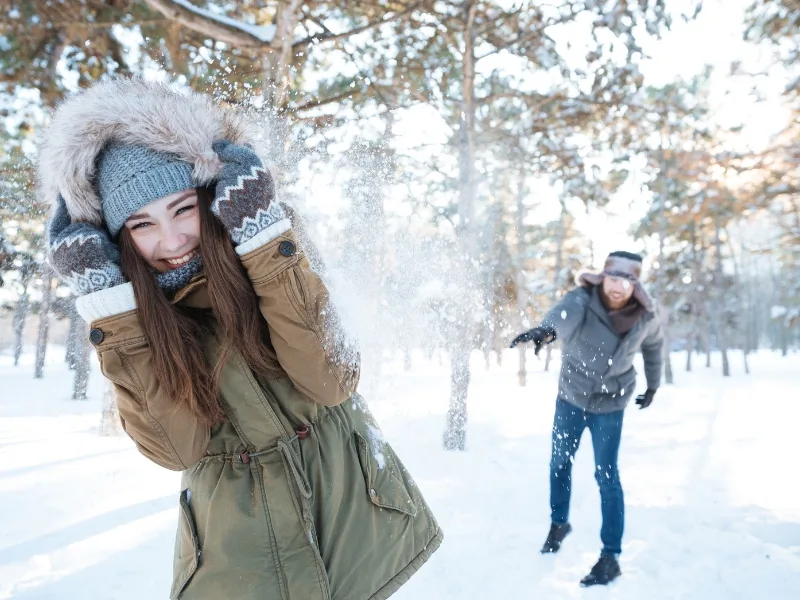 Winter snowball fight with a woman and a man who are both smiling.