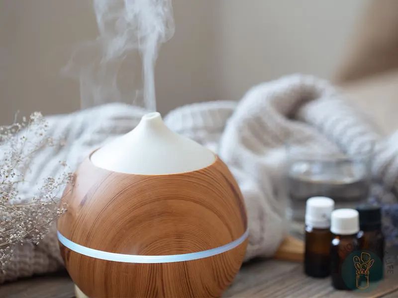 Essential oil diffuser diffusing mist with white knitted cloth as background.