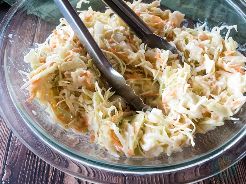 Copycat popeyes coleslaw dressing in a glass bowl on a wooden table.