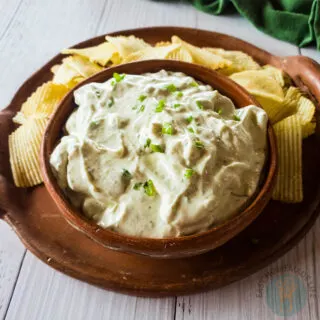 A bowl of lawson's chip dip on a clay plate with chips.