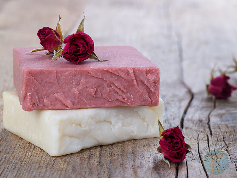 Two bars of soap stacked with roses on top of them.
