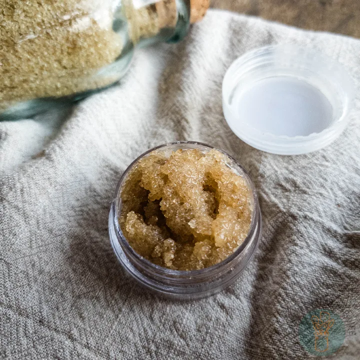 Brown sugar lip scrub in small container without lid on cloth napkin.