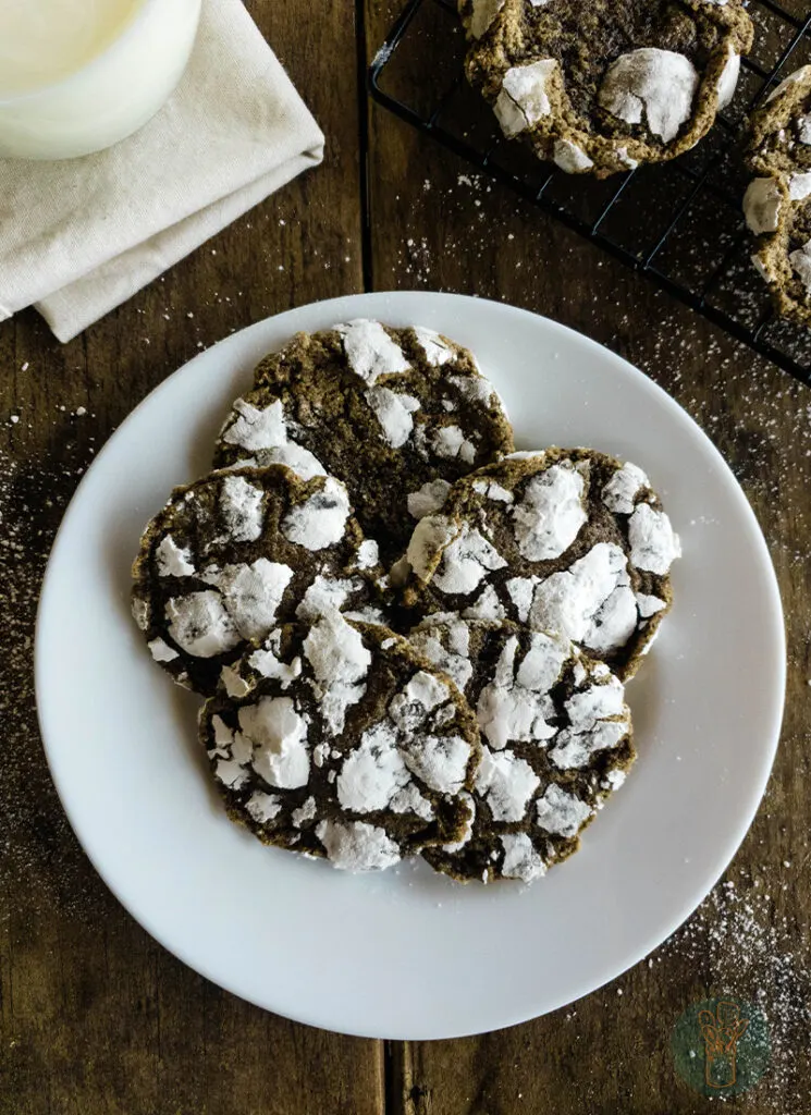 Five chai cookies on a plate next to a glass of milk.