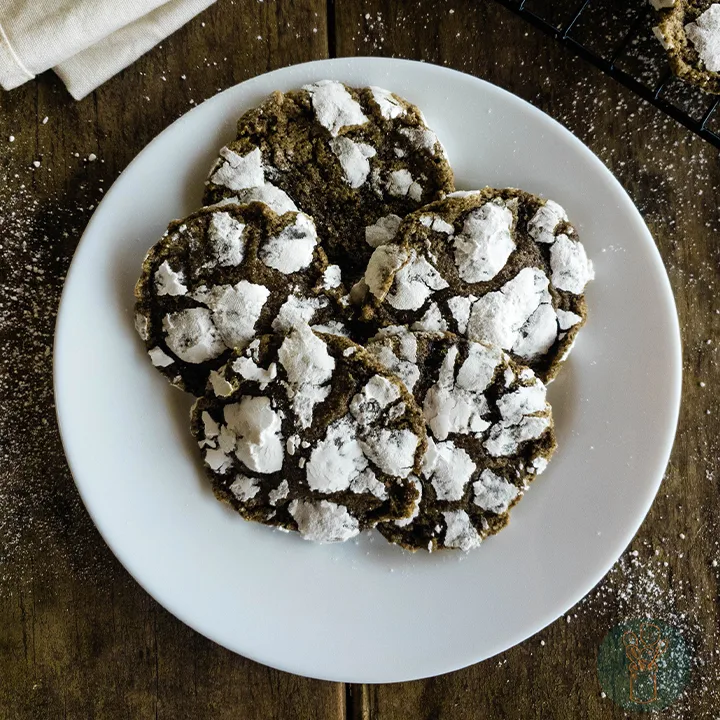 Crinkle cookies on a plate with powdered sugar.