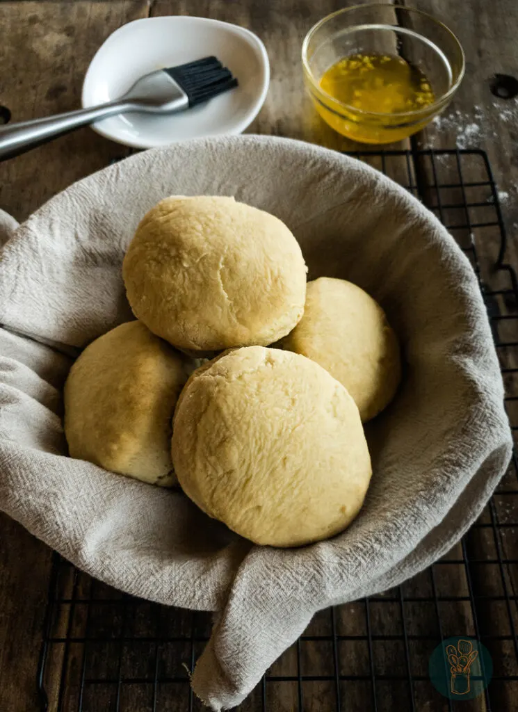 Biscuits in a cloth lined bowl on a wire rack.