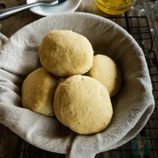 Bread rolls in a bowl on a wire rack.