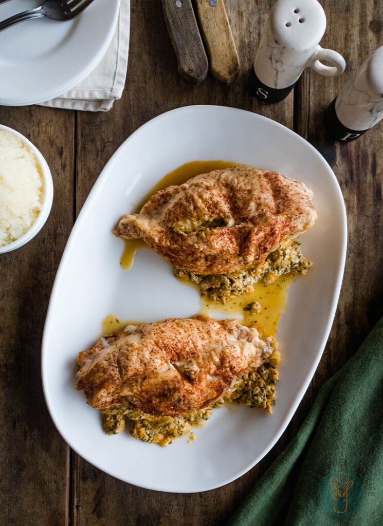 Two chicken breasts on a plate with mashed potatoes.