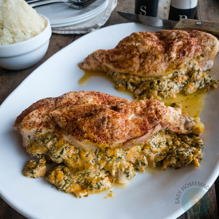 Two stuffed chicken breasts on a white plate next to salt and pepper shaker.