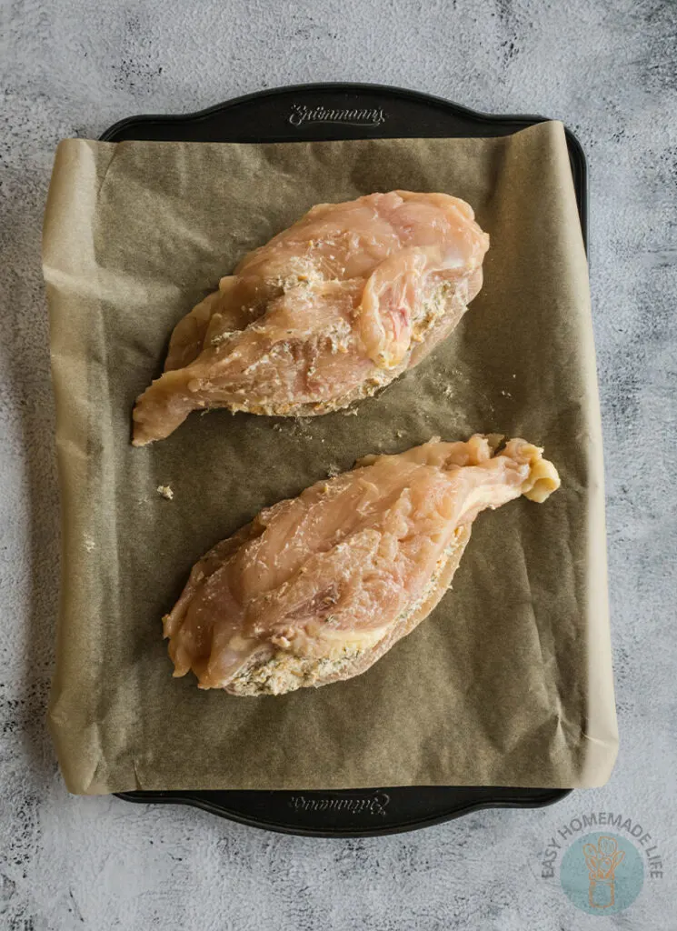 Two chicken breasts on a baking sheet with parchment paper.