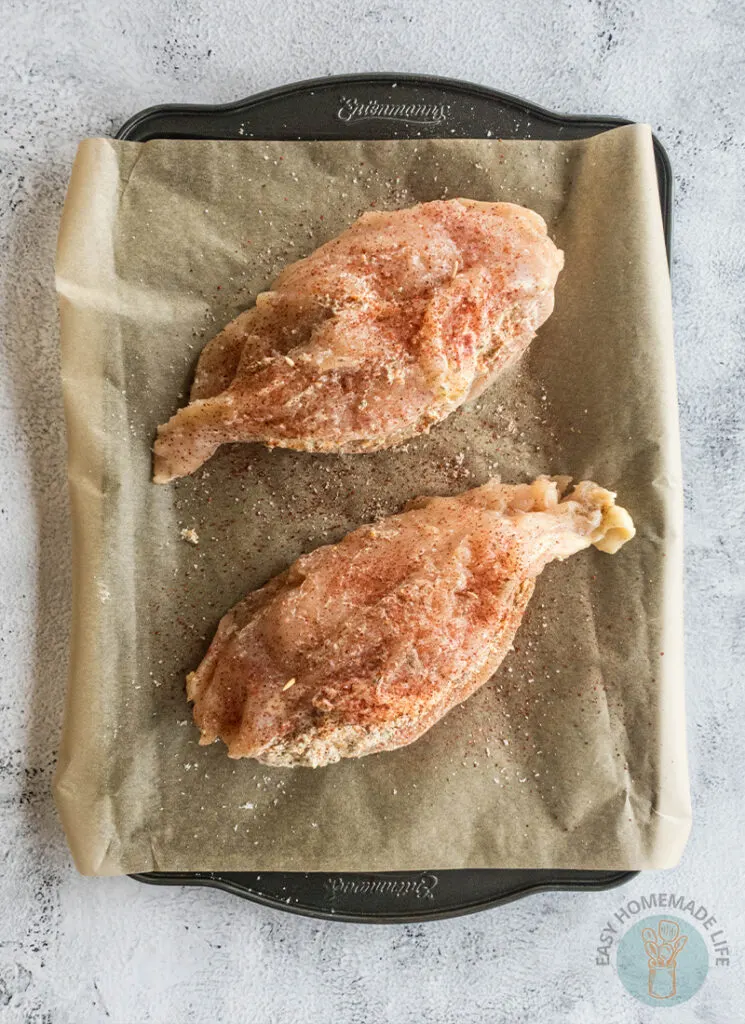 Two pieces of chicken on a baking sheet.