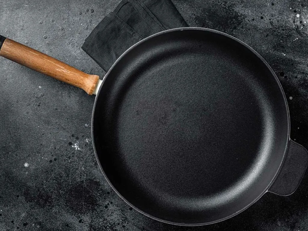A clean cast iron skillet with wooden handle.