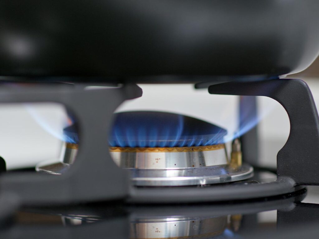 Gas stove with a blue flame, demonstrating the process of cleaning a cast iron skillet.