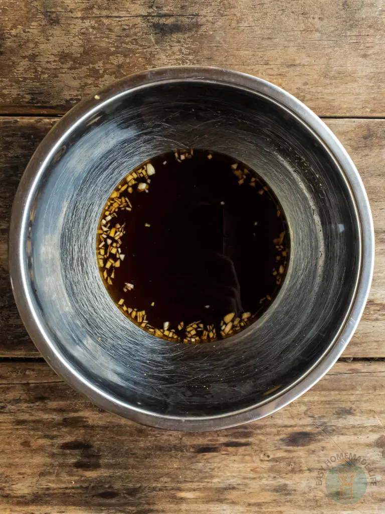 A stainless steel bowl with black sauce in it.