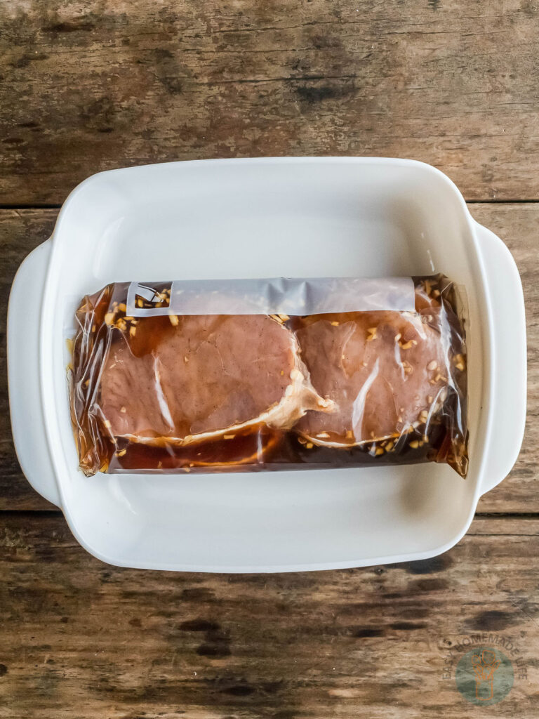 Smoked ham in a white dish on a wooden table, accompanied by pineapple.