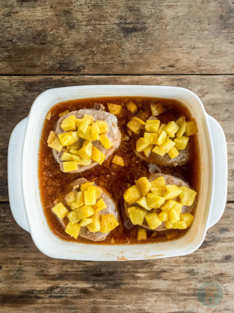 white baking dish holding teriyaki marinated pineapple pork chops with pineapple topping