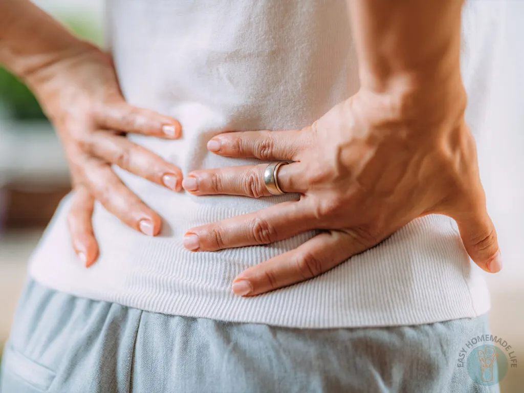 A woman holding her lower back with two hands.