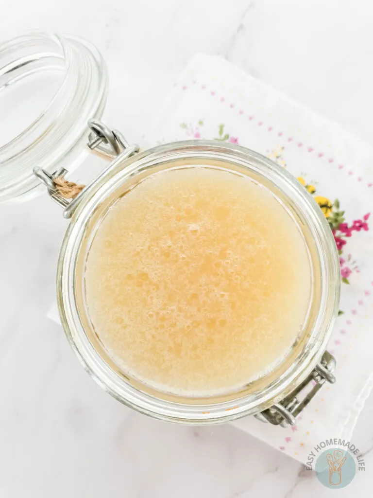 diy honey sugar scrub recipe in a glass flip-top jar on a pretty cloth napkin