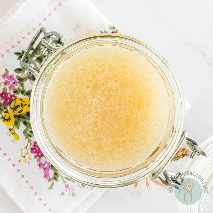 An opened jar of honey body scrub on a napkin with floral design.