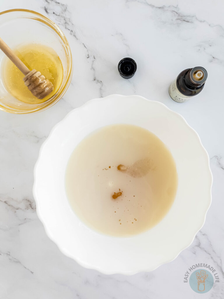 adding essential oils to the mixing bowl for milk and honey body scrub recipe