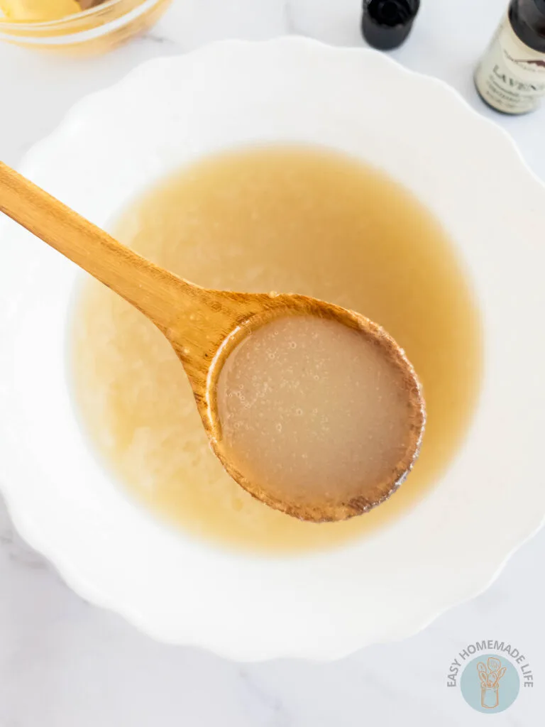 A spoonful of honey body scrub being raised from a bowl of the same scrub.