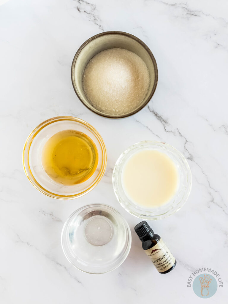 Honey body scrub ingredients in separate bowls and a bottle of lavender essential oil.