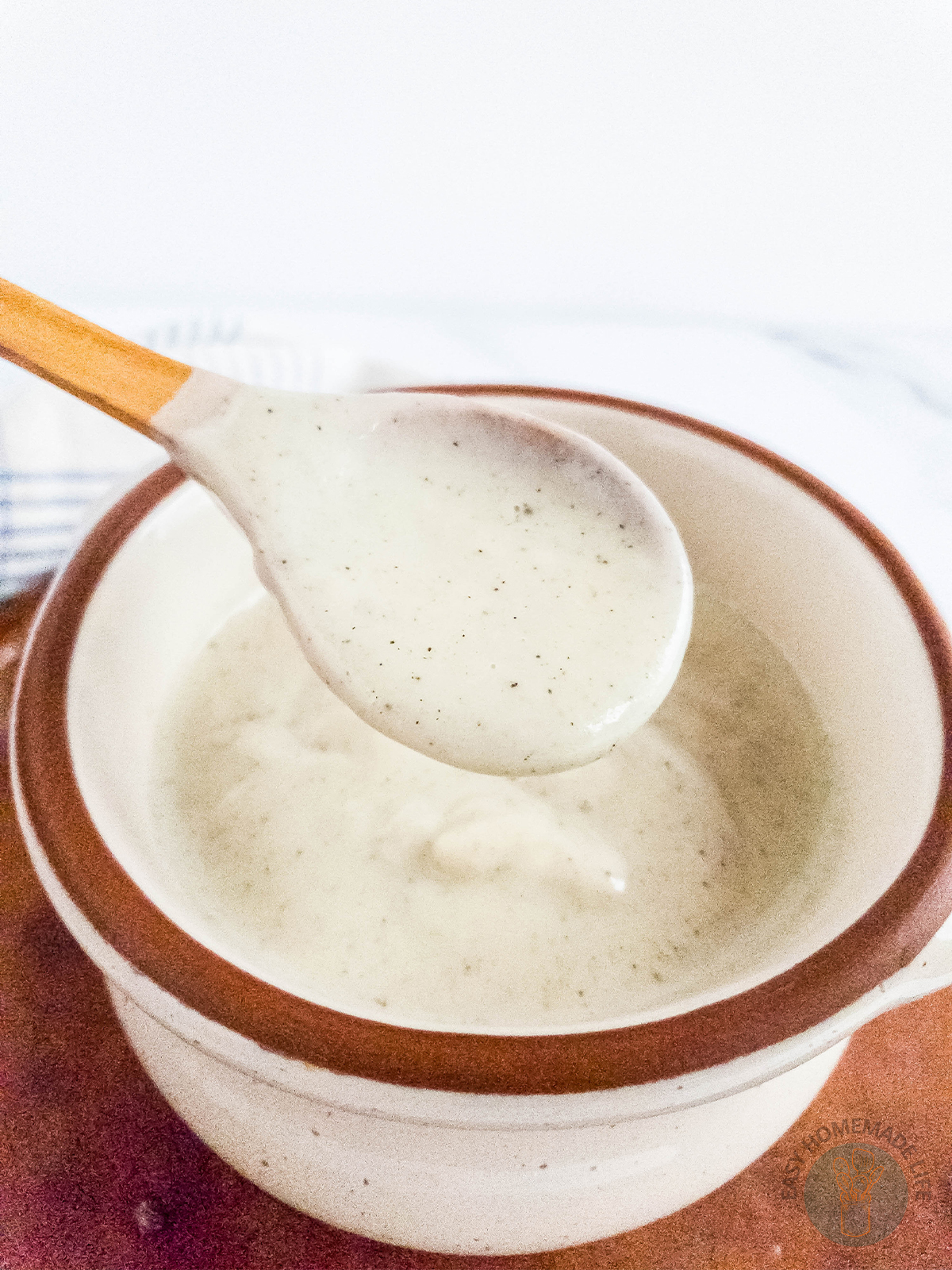 A bowl of creamy pepper gravy with a spoon being removed from it.