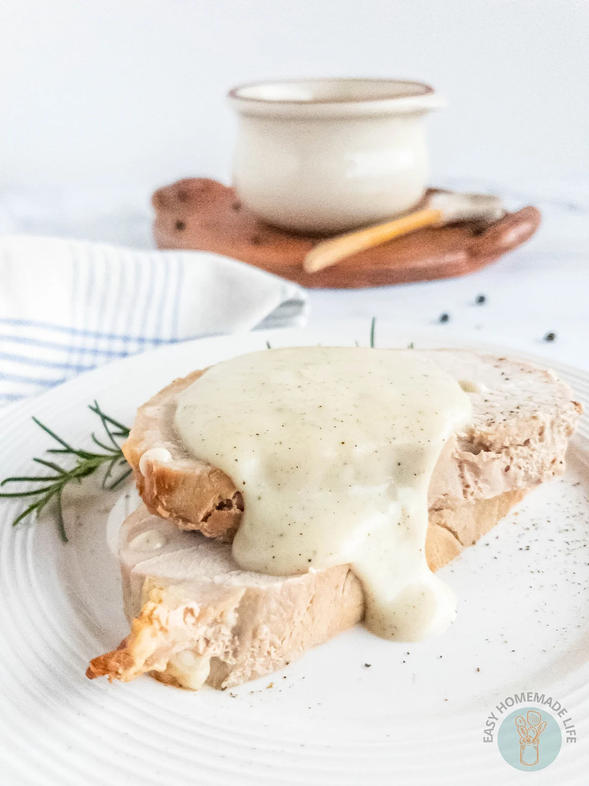 Pepper gravy on slices of meat on a white plate. A white soup bowl at the background.