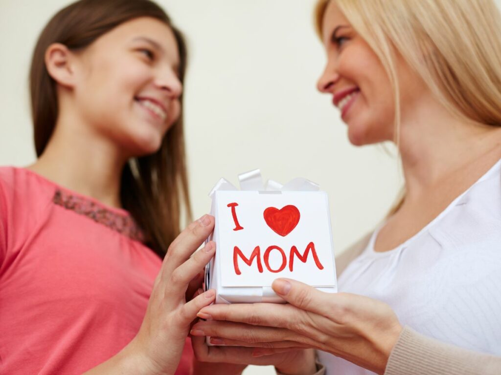 A girl giving a DIY gift to her mom that says I heart mom.