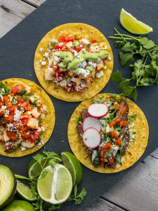 Three tacos with guacamole, radishes and limes.