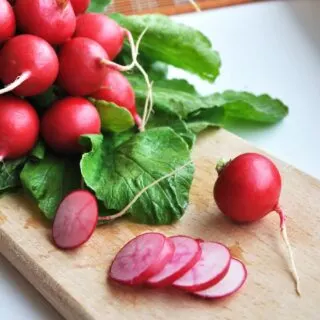 sliced radishes on a cutting board to prep for cooking