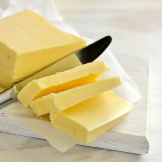 A stick of soft butter with a knife slicing through.