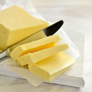 A stick of soft butter with a knife slicing through.