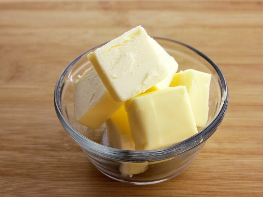Softened butter cubes in a glass dish.