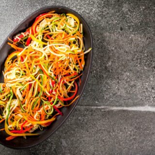 different color veggie noodles on a black platter