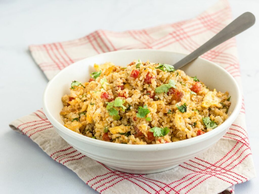 Cauliflower rice recipe in a bowl with fork and veggies.