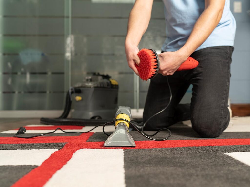 A man regularly using a vacuum cleaner on a carpet.