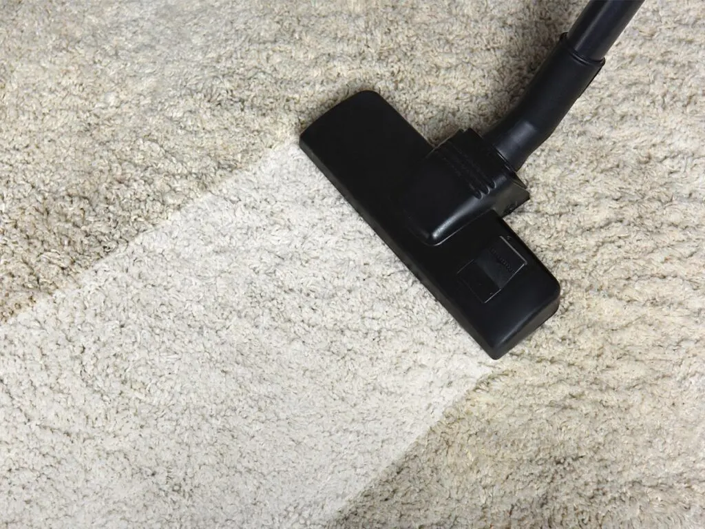 A vacuum cleaner is being used to clean a carpet.